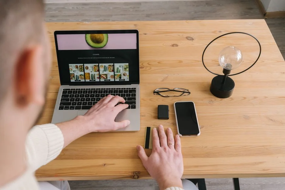 Close-up of hands interacting with a shopping website on a laptop screen indoors.